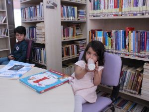 Bir ellerinde biberon, bir ellerinde kitap