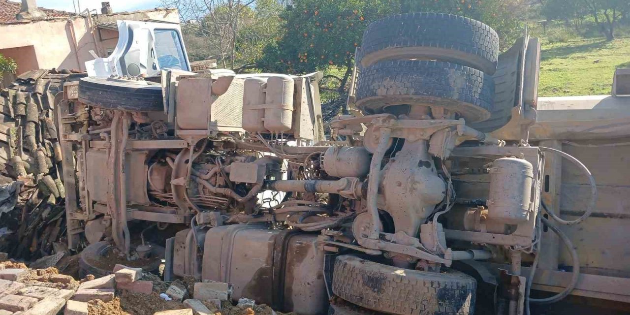 Otobüse çarpan kum yüklü kamyon, bir evin  bahçesine devrildi